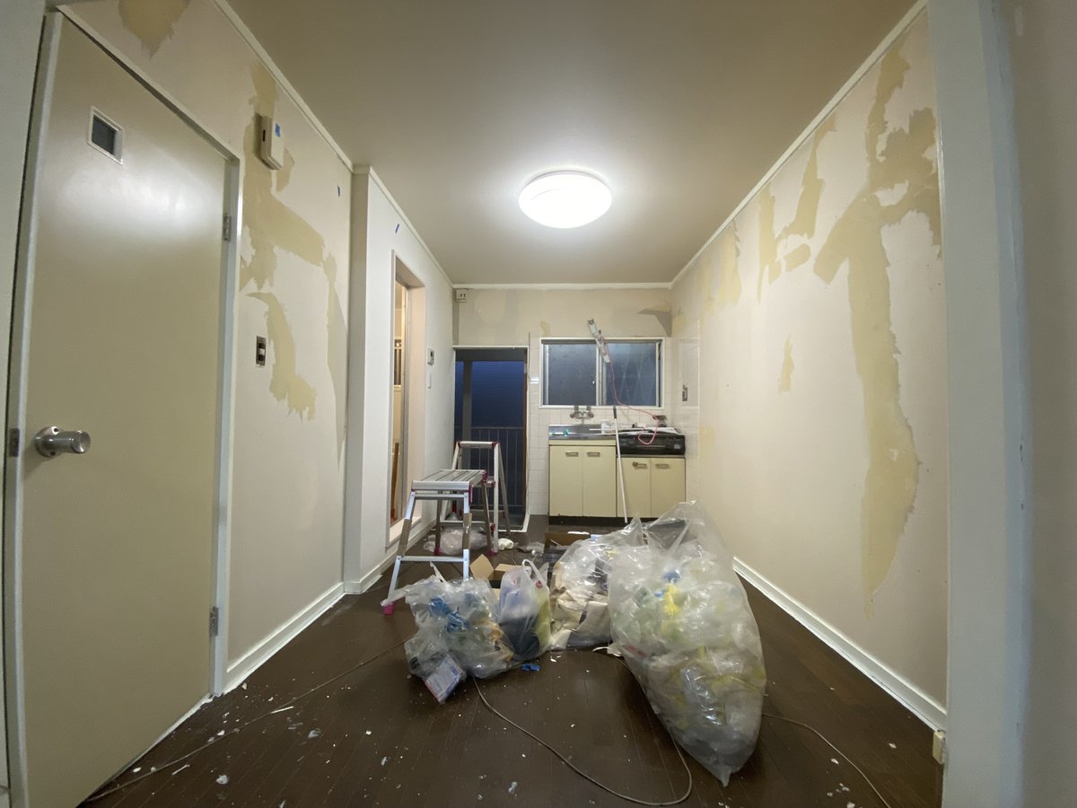 既存の壁紙を剥がしている途中の部屋。裏紙が壁に残った状態