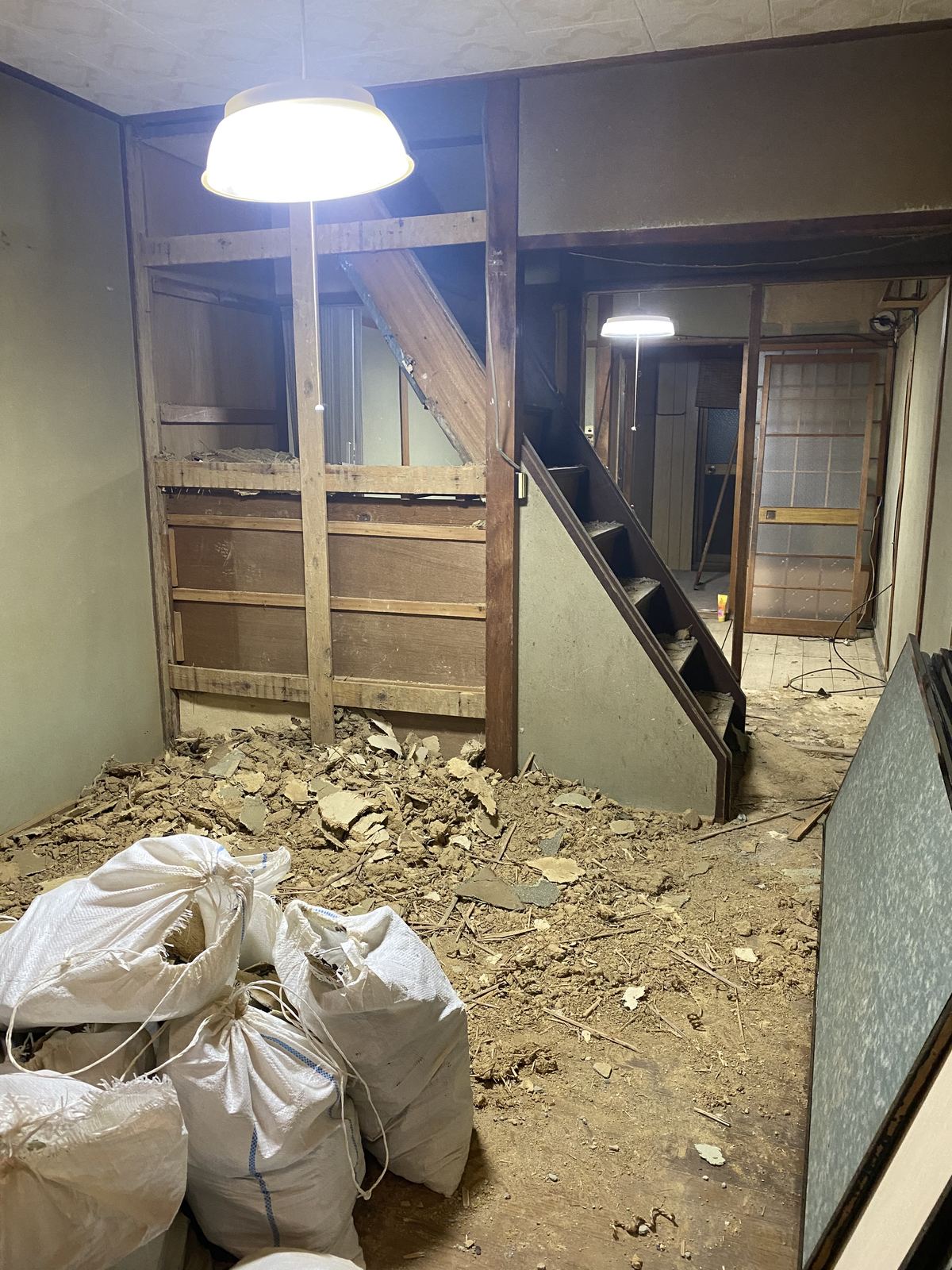 土壁を剥がした解体現場。大量の土のガラが床に積もり、土のう袋に詰めてある